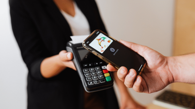 Pessoa realizando pagamento por aproximação usando smartphone em máquina de cartão