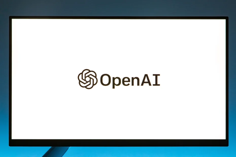 Monitor exibe o logotipo da OpenAI em um ambiente de estúdio com iluminação azul.