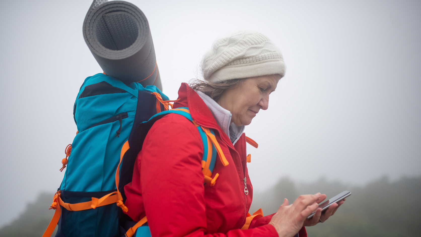 Pessoa usando smartphone antigo com mapa offline e navegação GPS durante caminhada ao ar livre.
