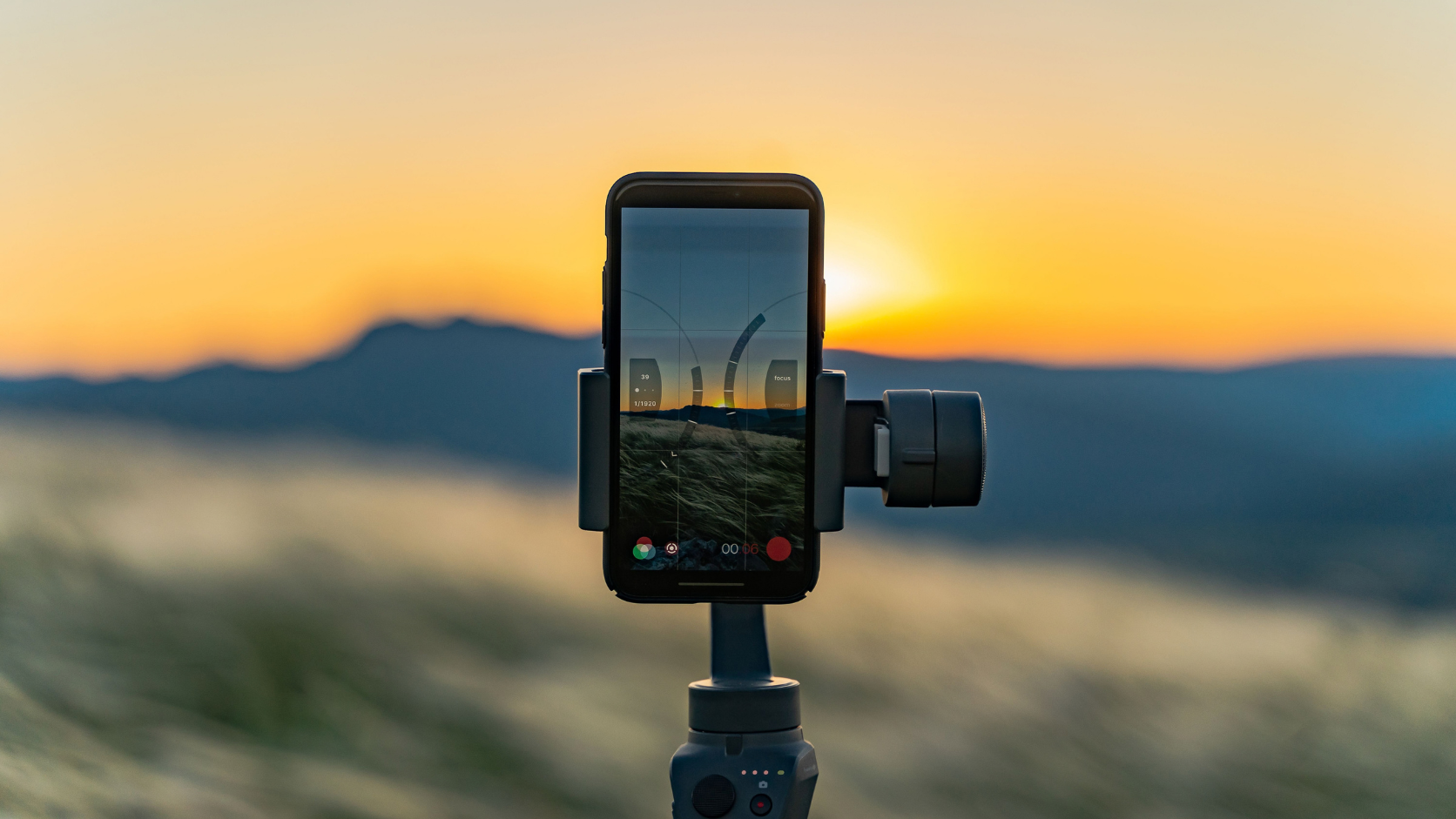 Smartphone em tripé posicionado para gravar vídeo em time-lapse do pôr do sol.